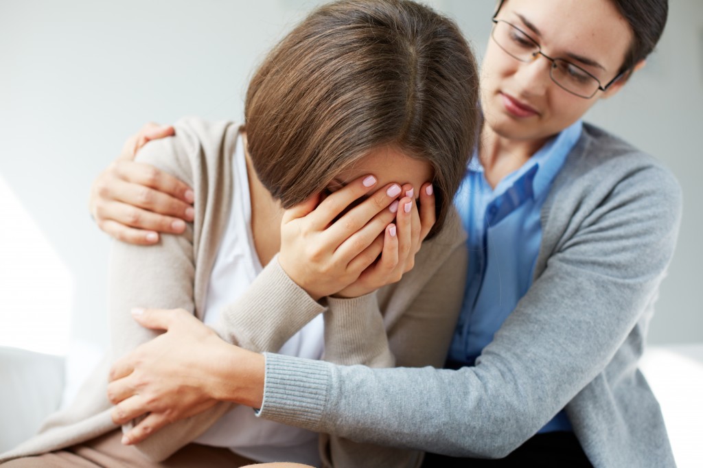 Image of compassionate psychiatrist comforting her crying patien