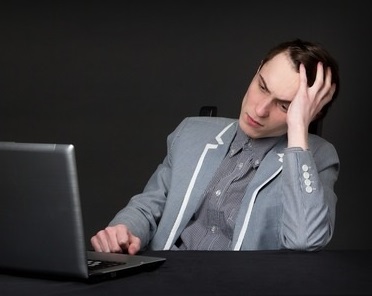 55549580 - tired caucasian guy sitting in front of computer, studio picture